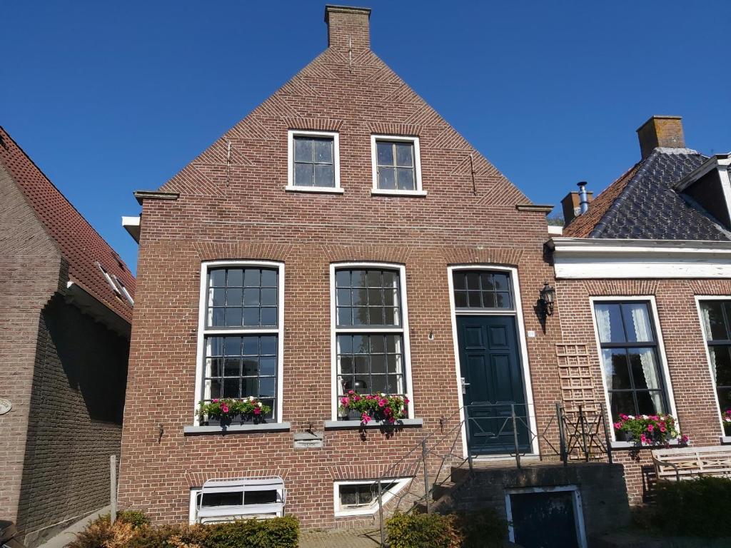 ein rotes Backsteinhaus mit Fenstern und Blumen auf dem Balkon in der Unterkunft De Wachtkaemer in De olde banck in Stavoren