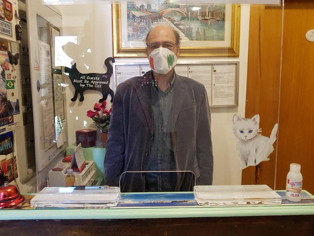a man standing behind a counter with a mask on his face at Hotel Adua in Venice