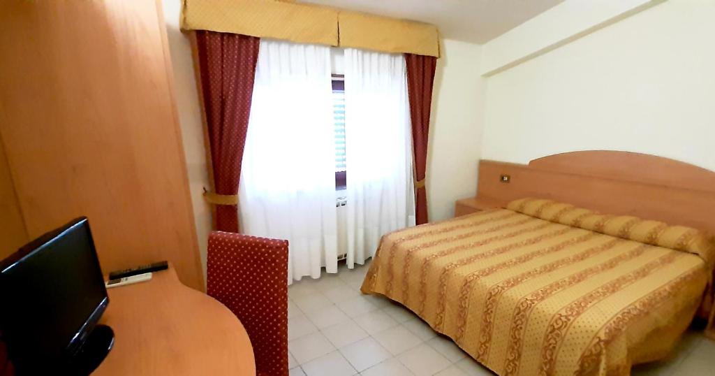 a bedroom with a bed and a desk with a television at L'Oliveto in Cineto Romano
