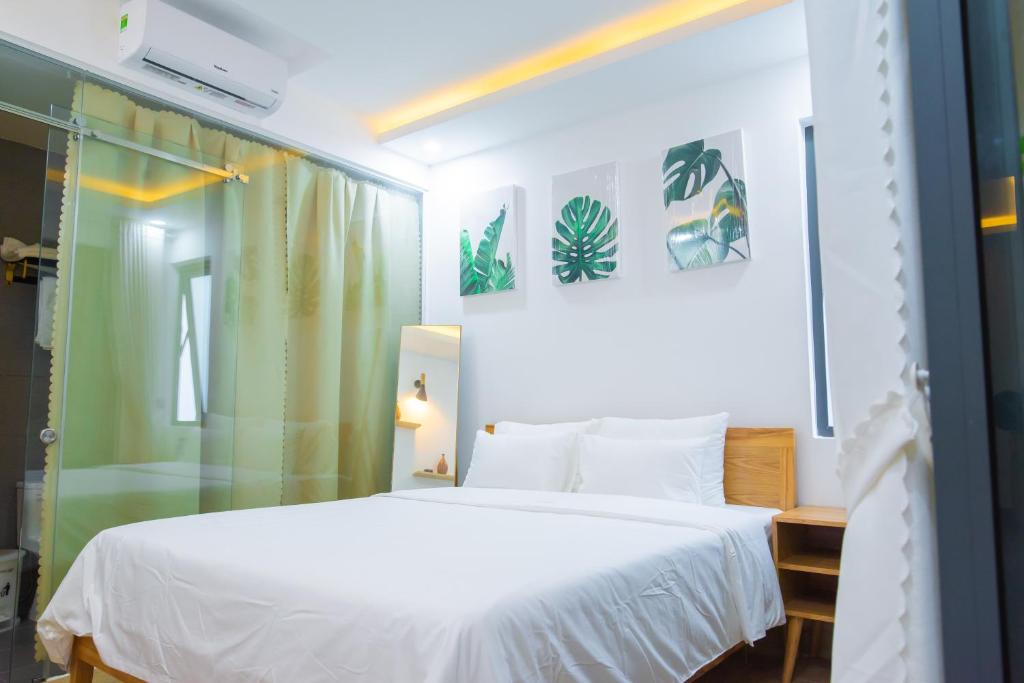 Schlafzimmer mit einem weißen Bett und einer Glasdusche in der Unterkunft Mộc House Homestay in Đà Nẵng