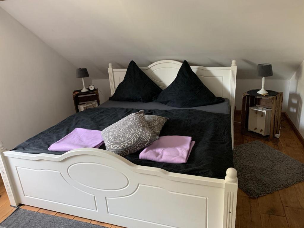uma cama branca com almofadas roxas em Land-Ruhe em Heidkamp
