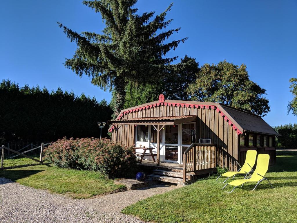 a small cabin with two chairs in the grass at Chalets des Trois Hêtres in Plombières-les-Bains