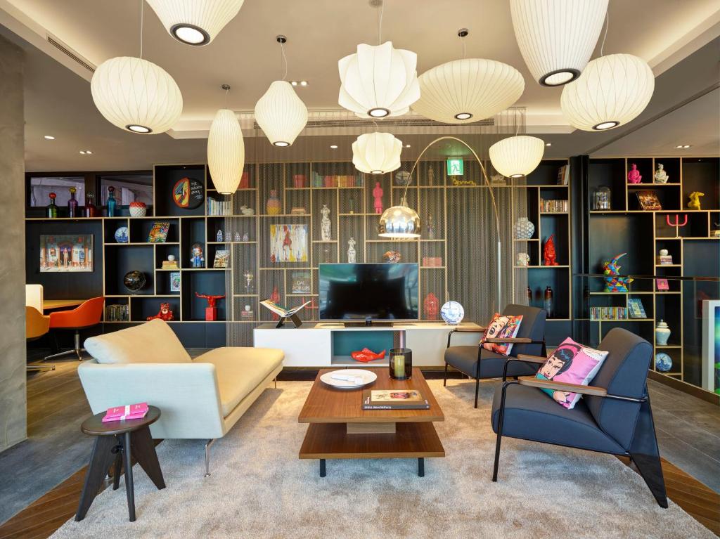 a living room with a couch and chairs and a tv at citizenM Taipei North Gate in Taipei