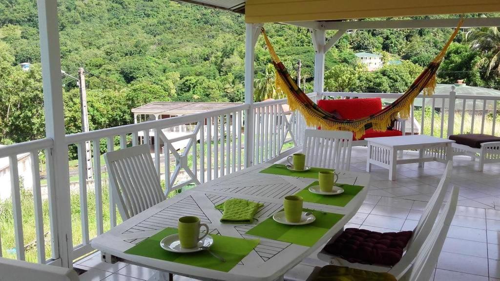 een witte tafel en stoelen op een veranda met een hangmat bij Maison de 5 chambres a Bas Vent a 500 m de la plage avec vue sur la mer jardin amenage et wifi in Bas Vent