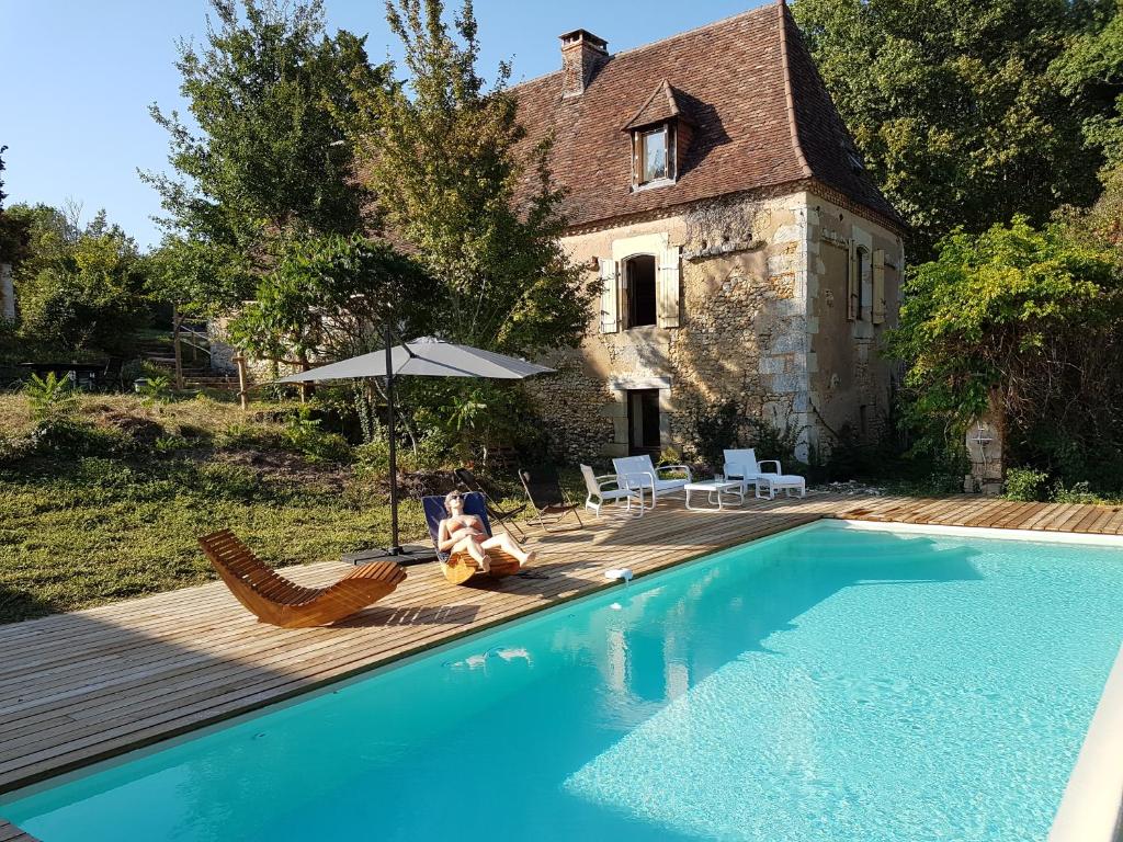 a person sitting in chairs next to a swimming pool at Gîte de Chantegrel in Fleurac