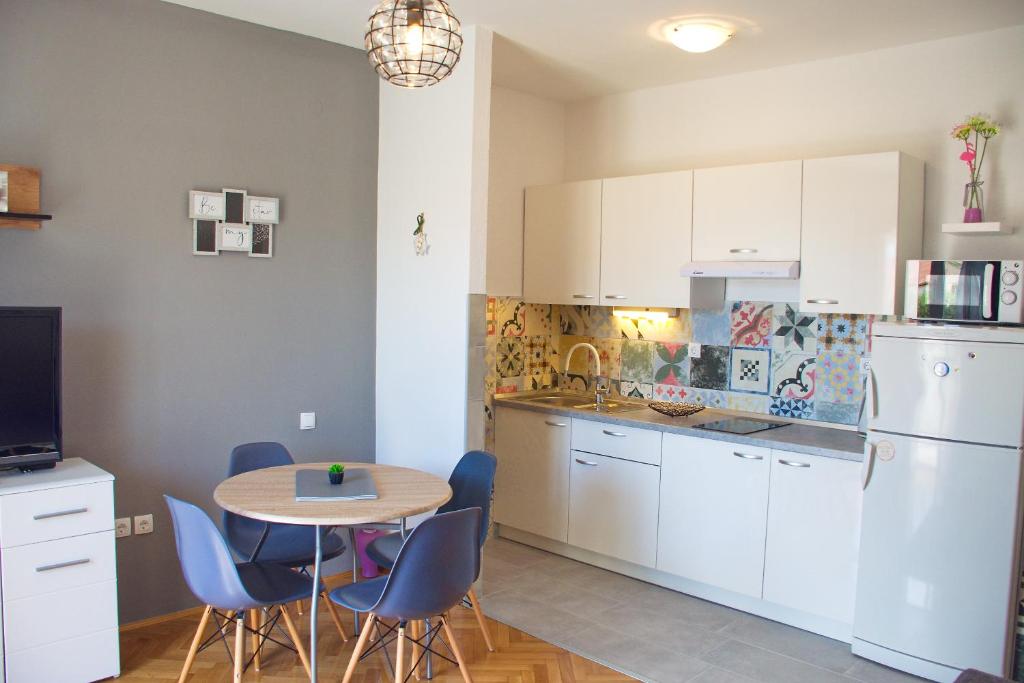 a kitchen with white cabinets and a table and chairs at Apartments Mike in Novalja