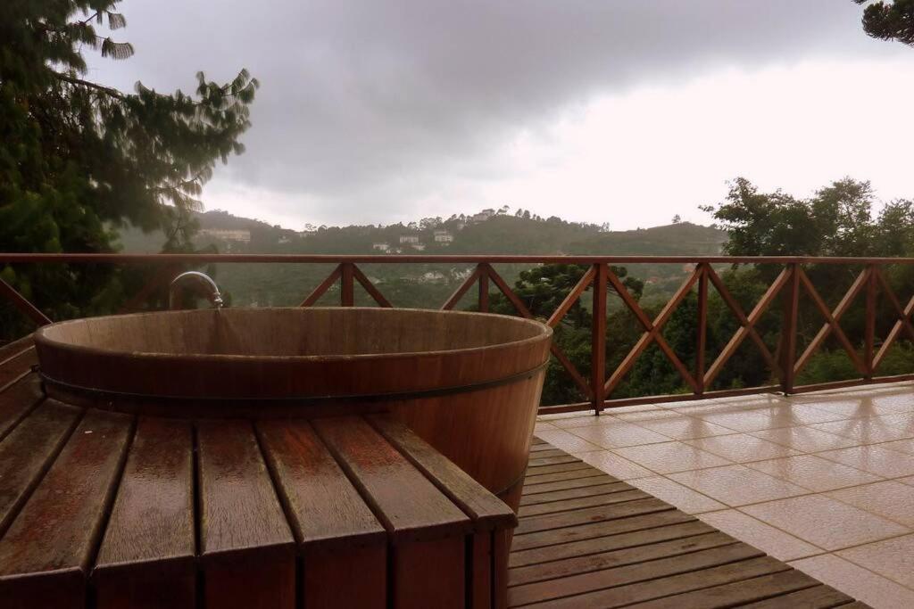 a wooden tub sitting on a deck with a view at casinha linda campos do jordão in Campos do Jordão