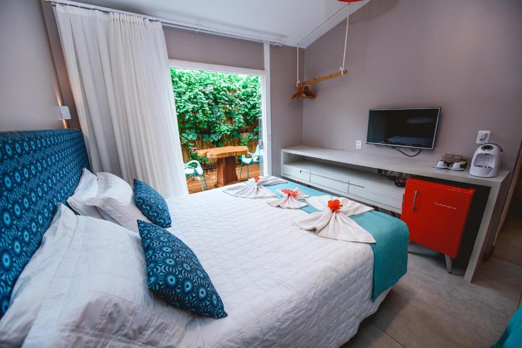 a bedroom with a bed with blue pillows and a television at Pousada Verdes Mares in Fernando de Noronha