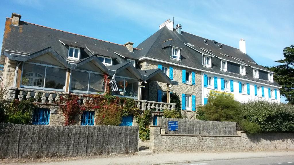 een groot huis met blauwe ramen en een hek bij Home des Pins SARL in Saint-Pierre-Quiberon