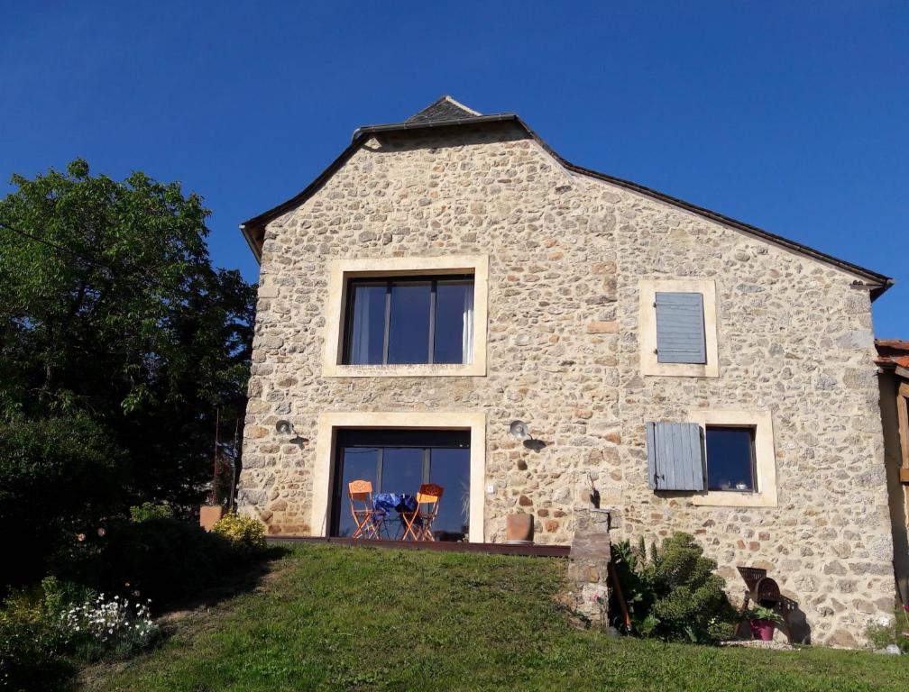 a stone house with two chairs on a lawn at La Croisée des Arts in La Bastide-lʼÉvêque