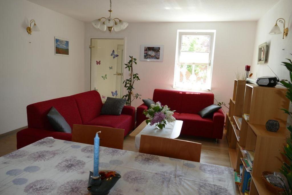 - un salon avec deux canapés rouges et une table dans l'établissement Ferienwohnung-Amsel-kinderfreundliche-Unterkunft-in-zentraler-Lage, à Bergen auf Rügen