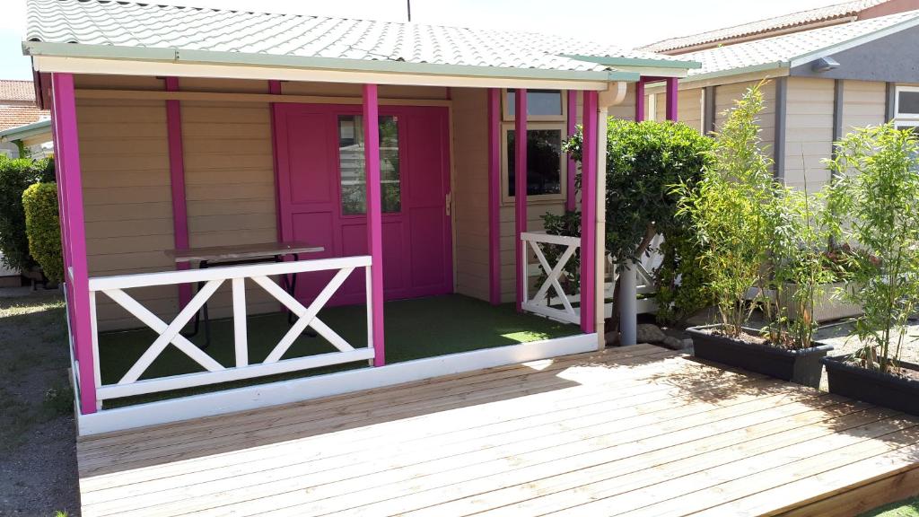 een klein huis met een roze deur en een veranda bij Les Chalets la Plage - Etape Vacances in Portiragnes