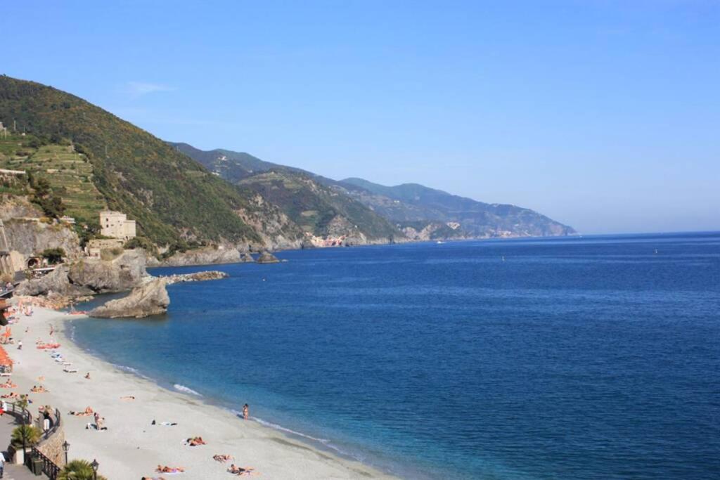 a beach with people on the sand and the water at Dall alba al tramonto in Monterosso al Mare
