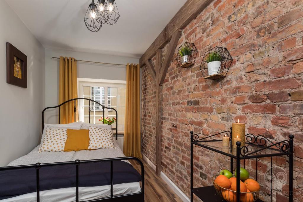 a bedroom with a brick wall and a bed with a basket of fruit at Goma Rent Długa Old Town Gdańsk in Gdańsk