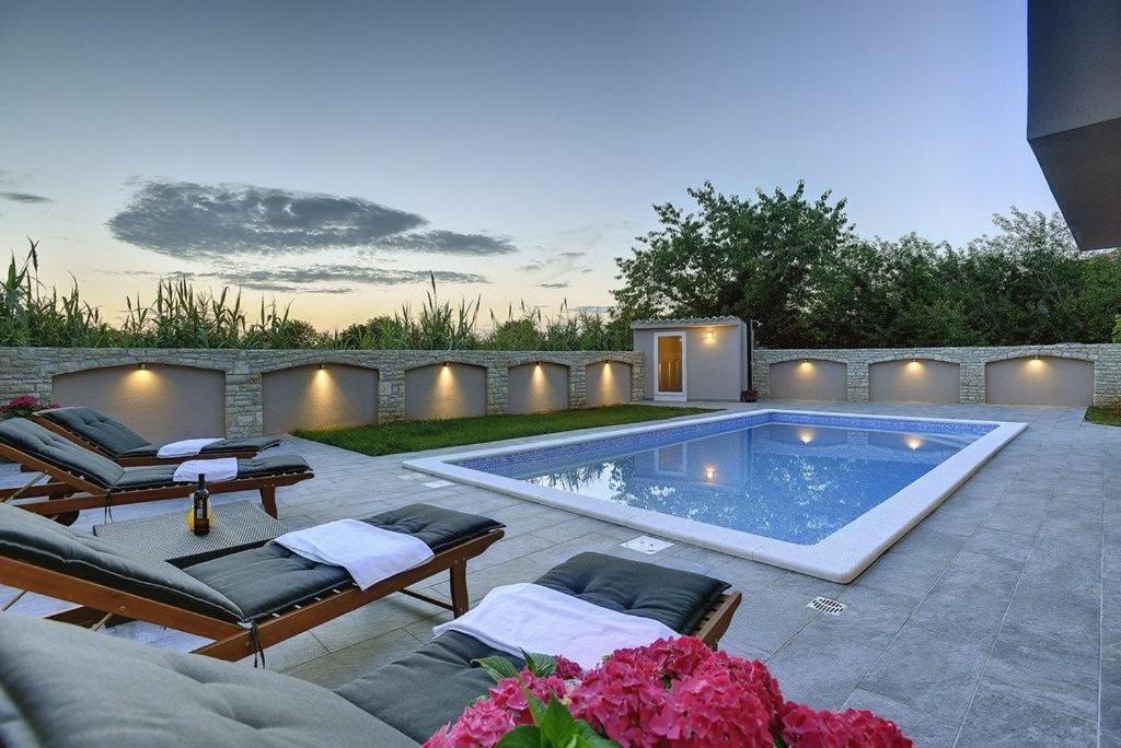 una piscina in un cortile con sedie a sdraio di Villa Nika a Fažana
