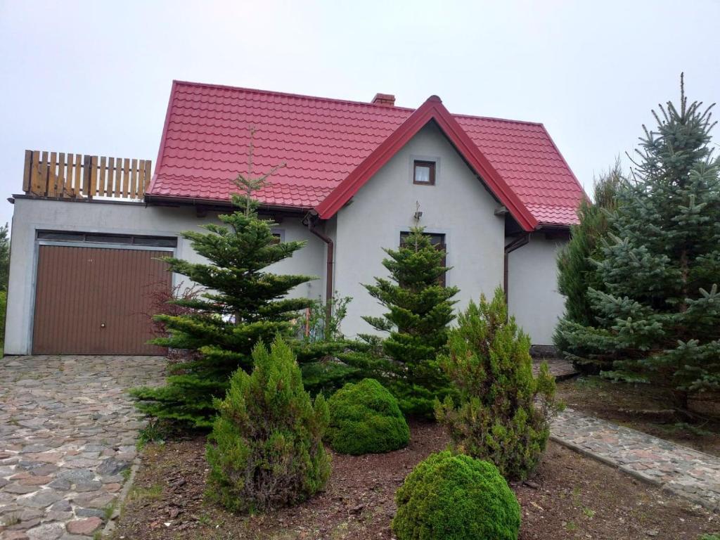 ein weißes Haus mit rotem Dach und einigen Bäumen in der Unterkunft Dom domek na Mazurach Jezioro Sasek Wielki Trelkówko Szczytno 1 in Kobyłocha