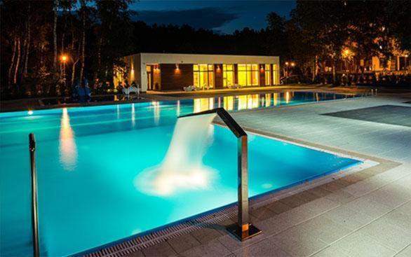 a large blue swimming pool at night with lights at Green Dream Polanki - Sauna & Bike & Bike room in Kołobrzeg