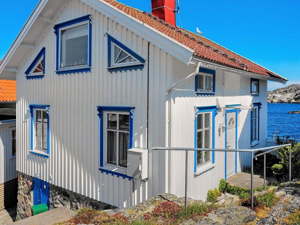 une maison blanche avec des fenêtres bleues à côté de l'eau dans l'établissement Holiday home Gullholmen III, à Gullholmen