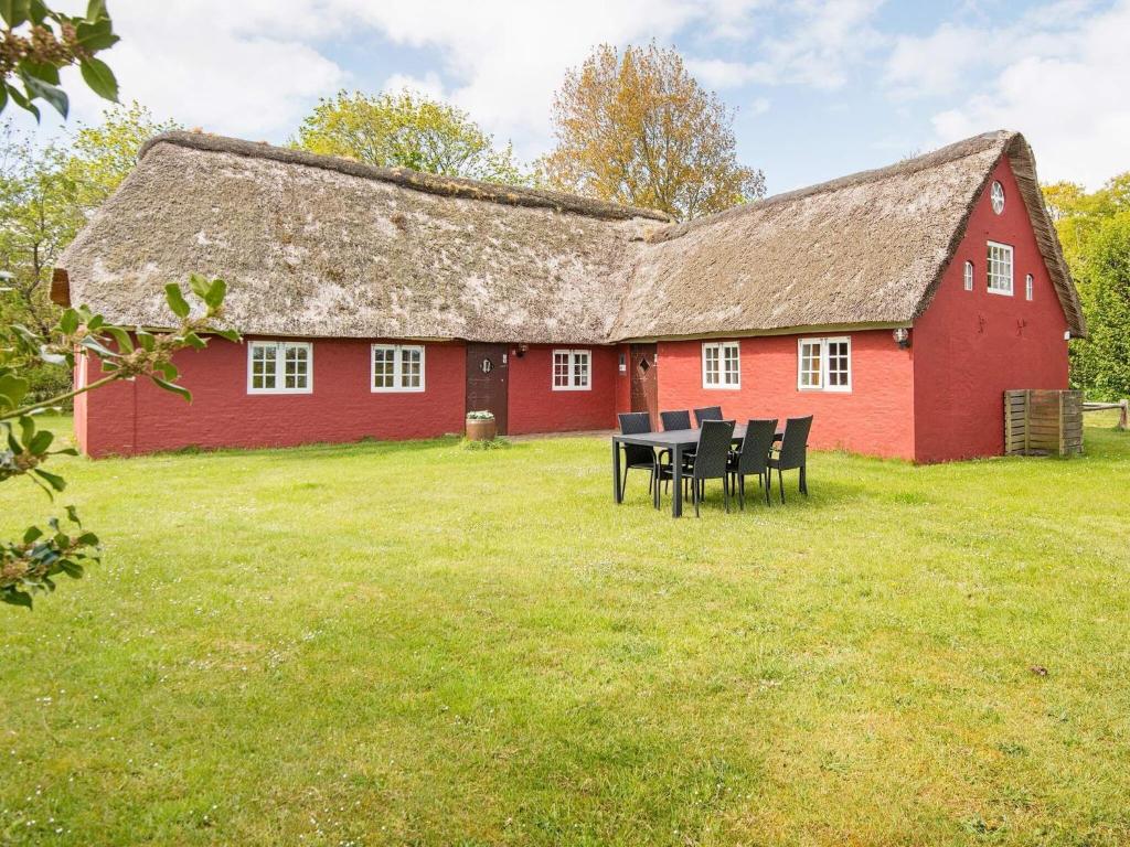 a red barn with a table and chairs in front of it at 6 person holiday home in R m in Rømø Kirkeby