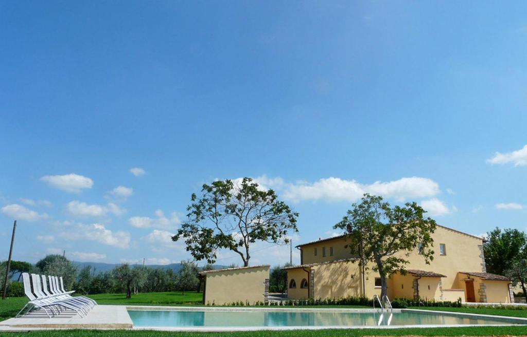 une piscine avec deux chaises et un bâtiment dans l'établissement Villa Pian De Noci - Tenuta del Palagio, à Mercatale Val Di Pesa