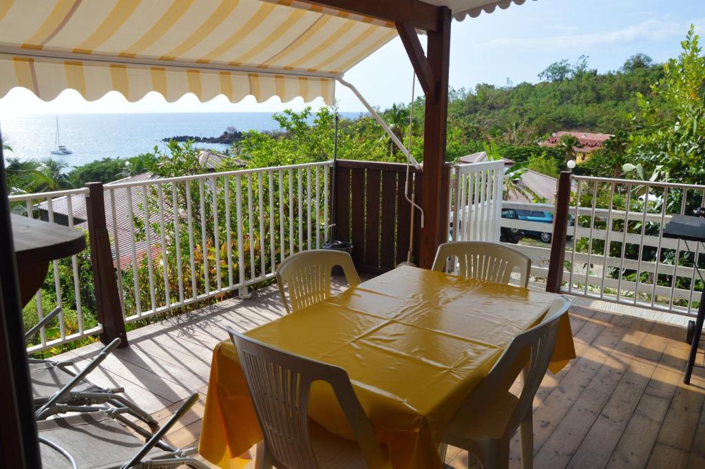 ブイヤントにあるBungalow de 2 chambres a Bouillante a 100 m de la plage avec vue sur la mer terrasse amenagee et wifiの黄色のテーブルと椅子が備わる海の景色を望むデッキ