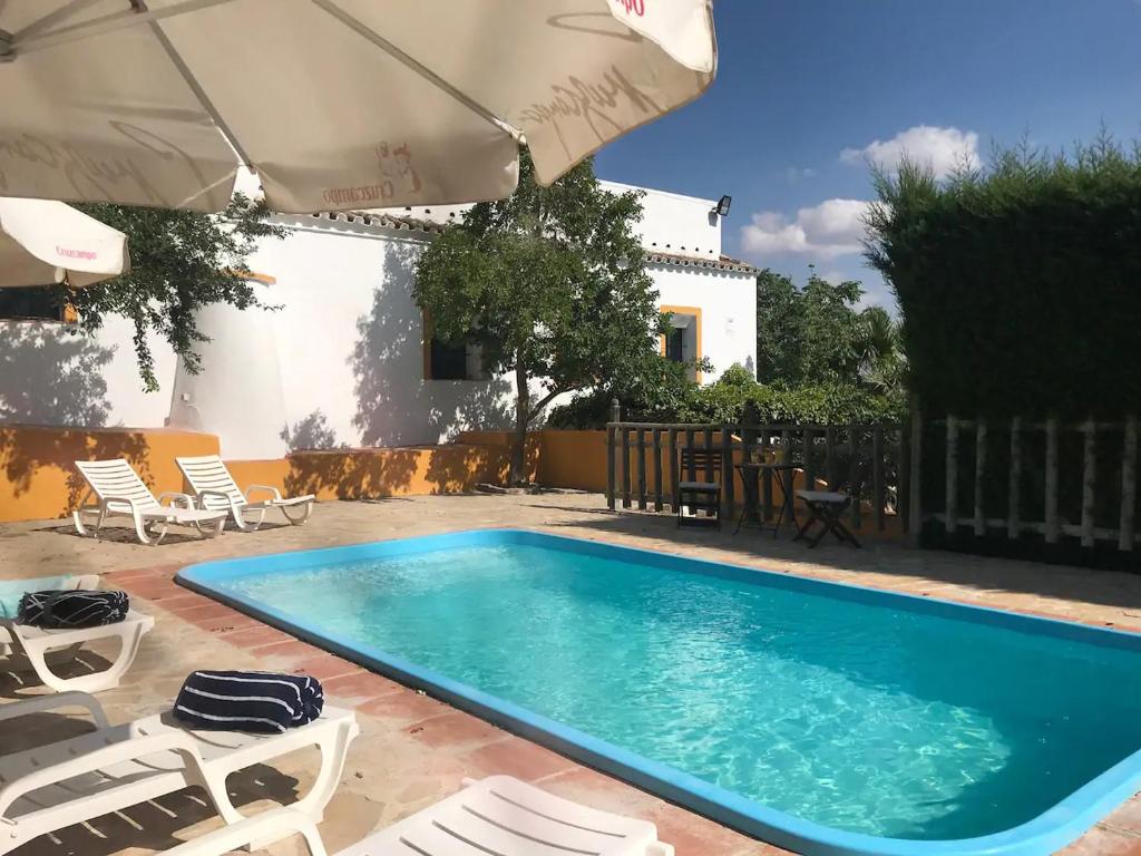 einen Pool mit Stühlen und einem Sonnenschirm in der Unterkunft 3 bedrooms villa with private pool and furnished terrace at El Saucejo in Saucejo