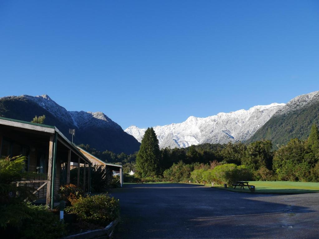 a parking lot with snow covered mountains in the background at Rainforest Motel in Fox Glacier