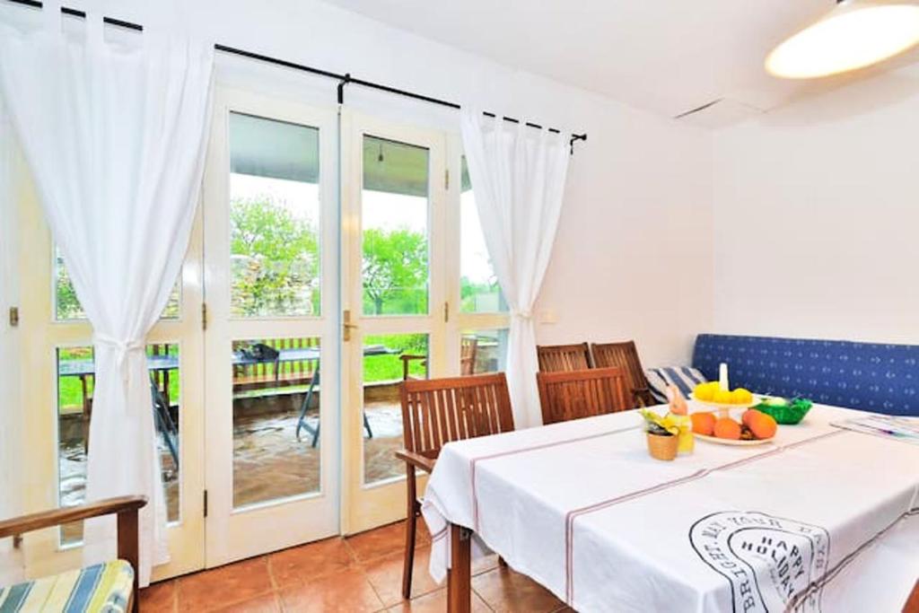 a dining room with a table and chairs and windows at Modern Apartment in Zambratija - 90 m² in Zambratija