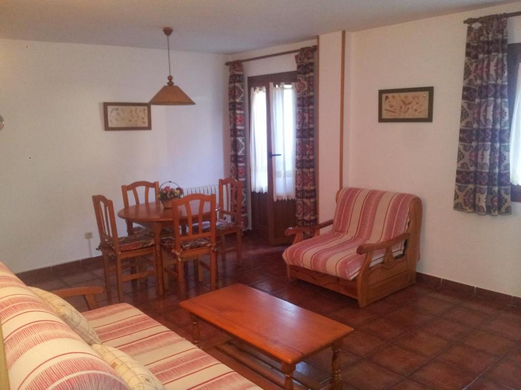una sala de estar con un sofá, una mesa y sillas en Apartamentos Petronilla, en Benasque