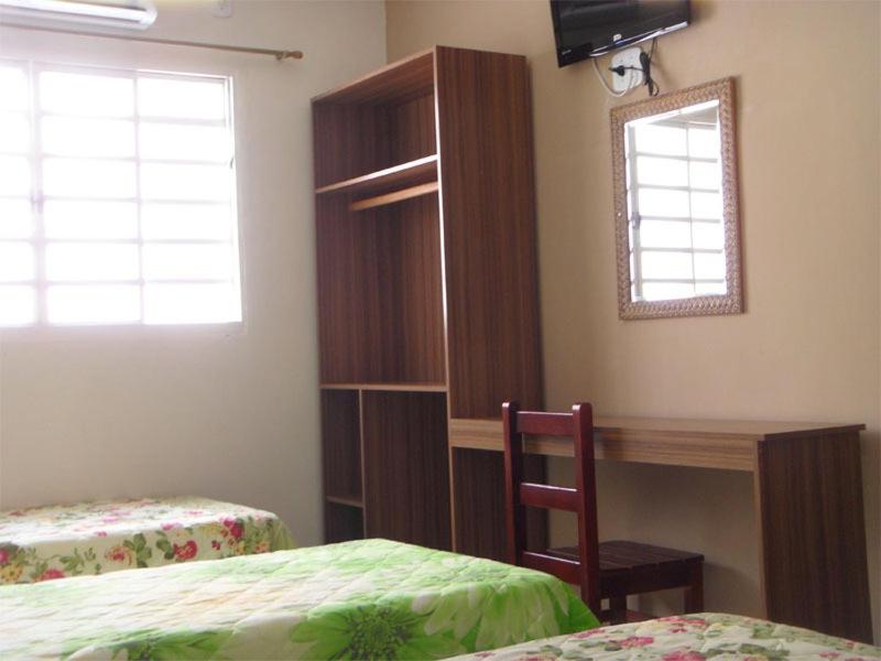 a bedroom with a desk and a bed and a desk and a window at Hotel Estação da Fé in Aparecida