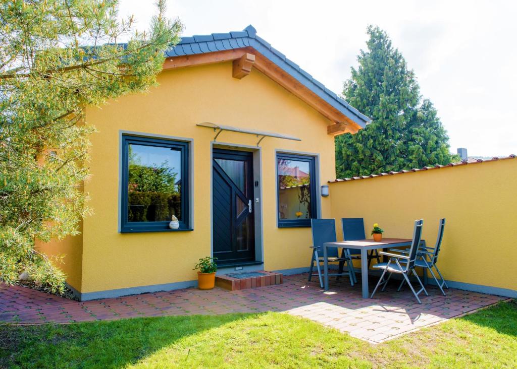 une petite maison jaune avec une table et des chaises dans l'établissement Ferienhaus Hexenschlummer - Schlafzimmer und romantischer Schlafboden, à Thale