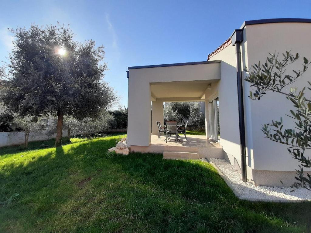 a small white building with a table in a yard at Holiday Home Aurora in Ližnjan