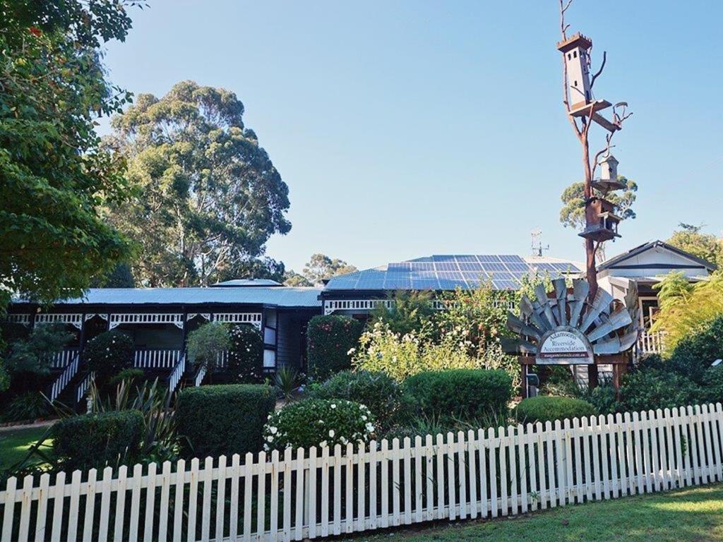 a white fence in front of a garden with a building at Adamsons Riverside Accommodation in Margaret River Town