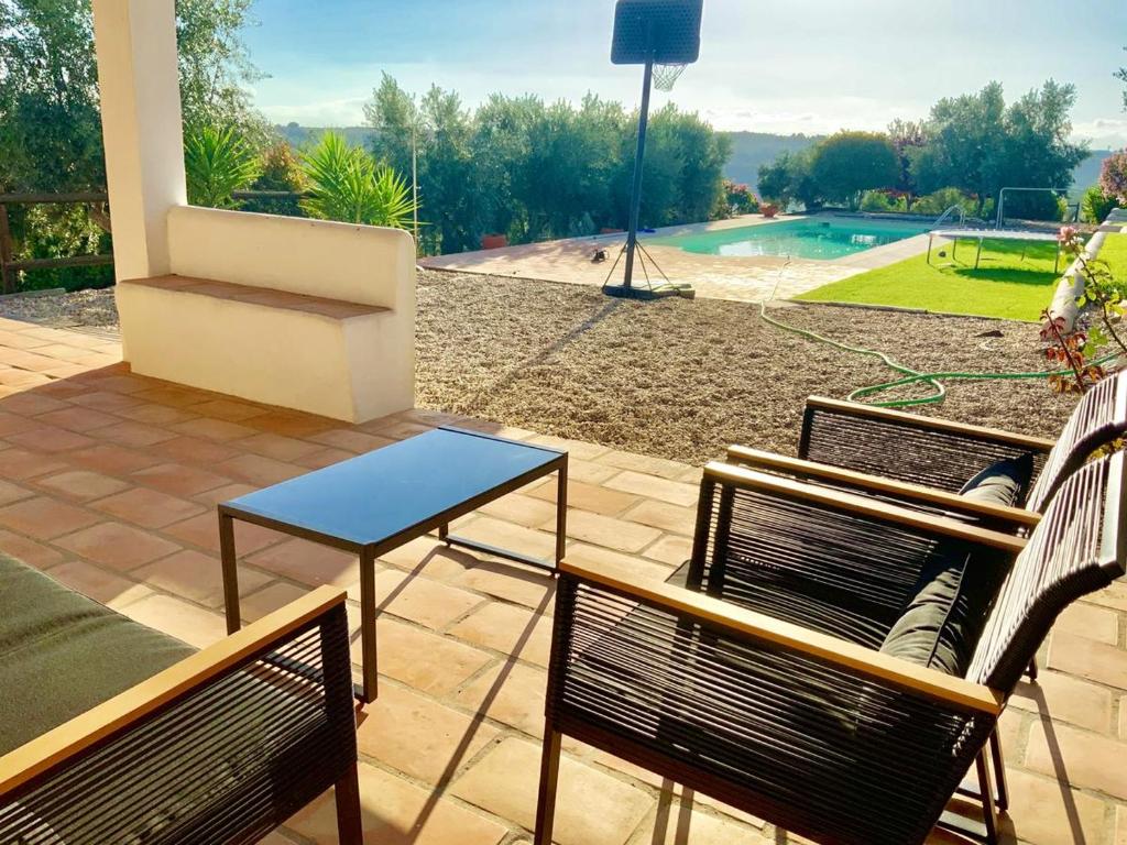 un patio con 2 sedie, un tavolo e una piscina di Charming Villa in Casais de São Bras with Mountain View a Casais de São Brás