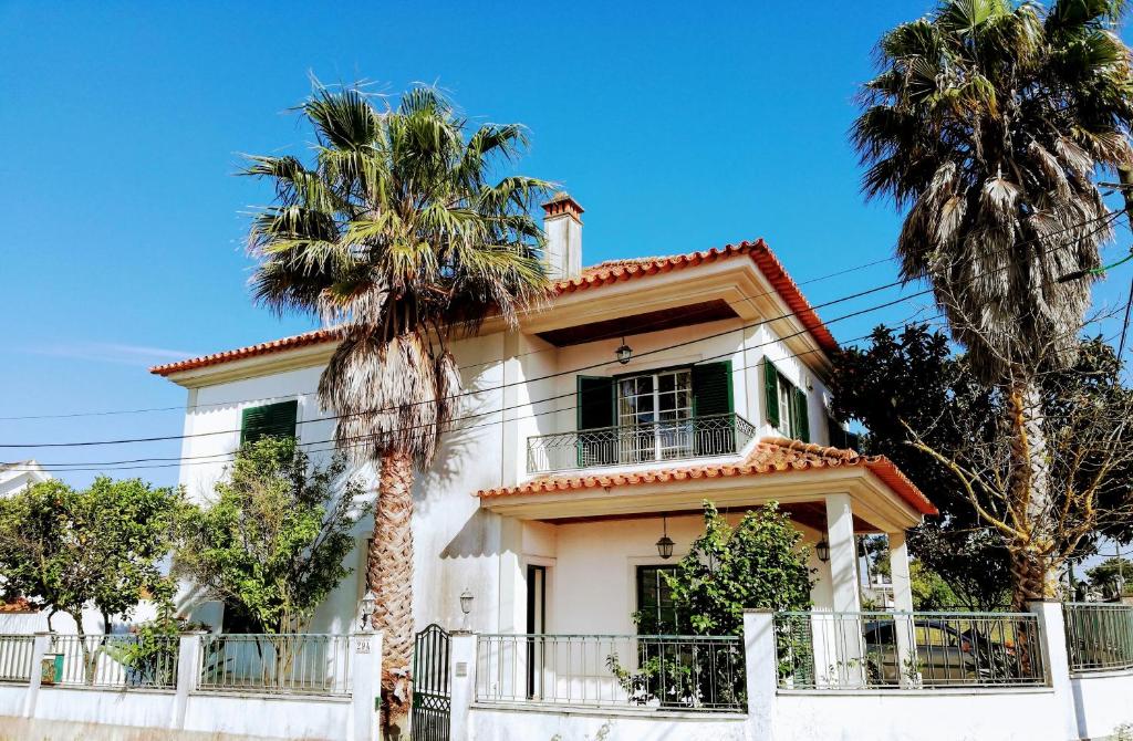 una casa bianca con palme di fronte di TripGeo Pinhal da Aroeira Villa ad Almada
