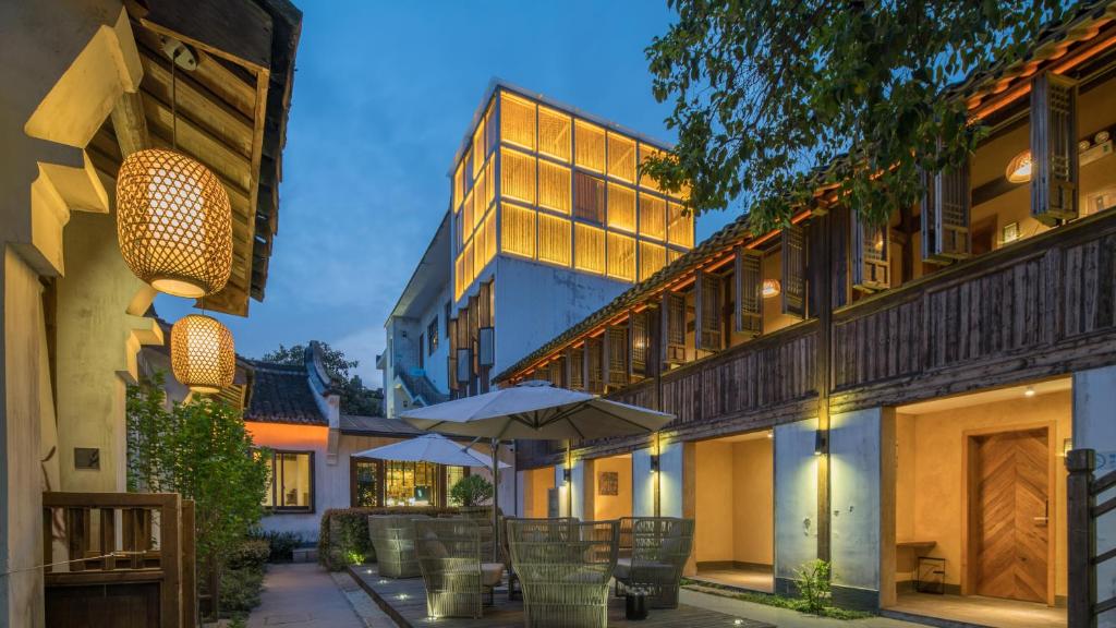 une cour avec des tables et des parasols dans un bâtiment dans l'établissement Floral Hotel · Yuexiang Inn Wuzhen, à Tongxiang