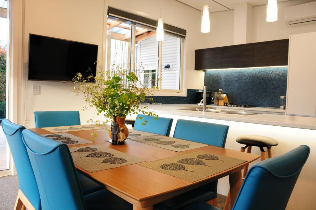 mesa de comedor con sillas azules y cocina en Fergus Hideaway en Te Anau