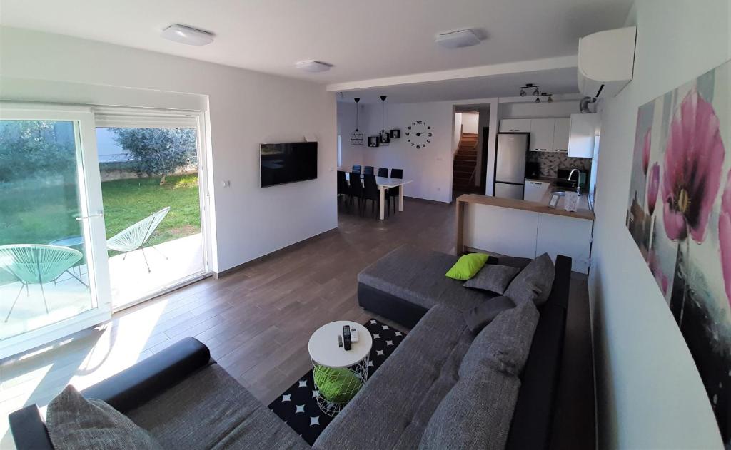 a living room with a large couch and a kitchen at Holiday Home Aurora in Ližnjan