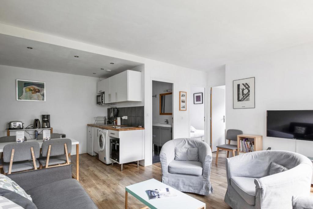 ein Wohnzimmer mit einem Sofa und Stühlen sowie eine Küche in der Unterkunft Appartement de la Motte - Welkeys in Paris