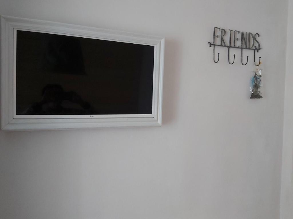 - une télévision à écran plat sur un mur blanc avec un panneau dans l'établissement Piccolo Appartamento Casa Vacanze B&B Angela, à Clusone