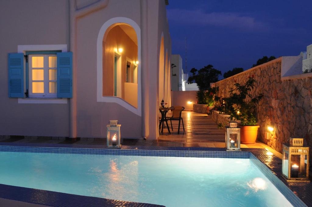 a swimming pool in front of a house at night at Villa Rose in Fira