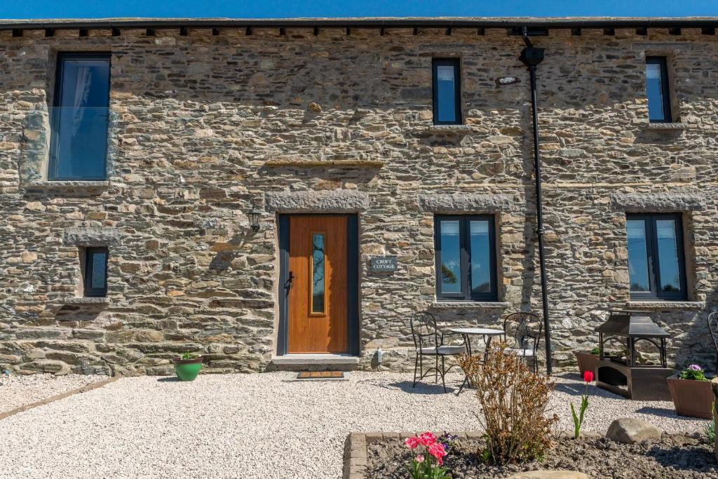 uma casa de pedra com uma porta de madeira e janelas em Croft Cottage em Skelsmergh