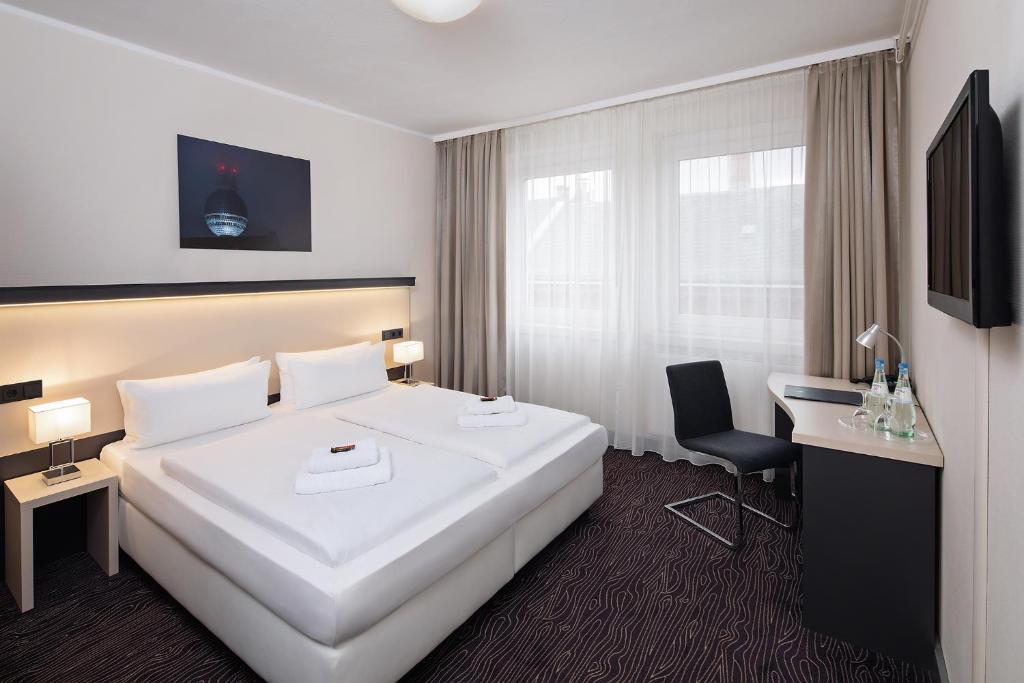 a hotel room with a large white bed and a desk at Dietrich-Bonhoeffer-Hotel Berlin Mitte in Berlin