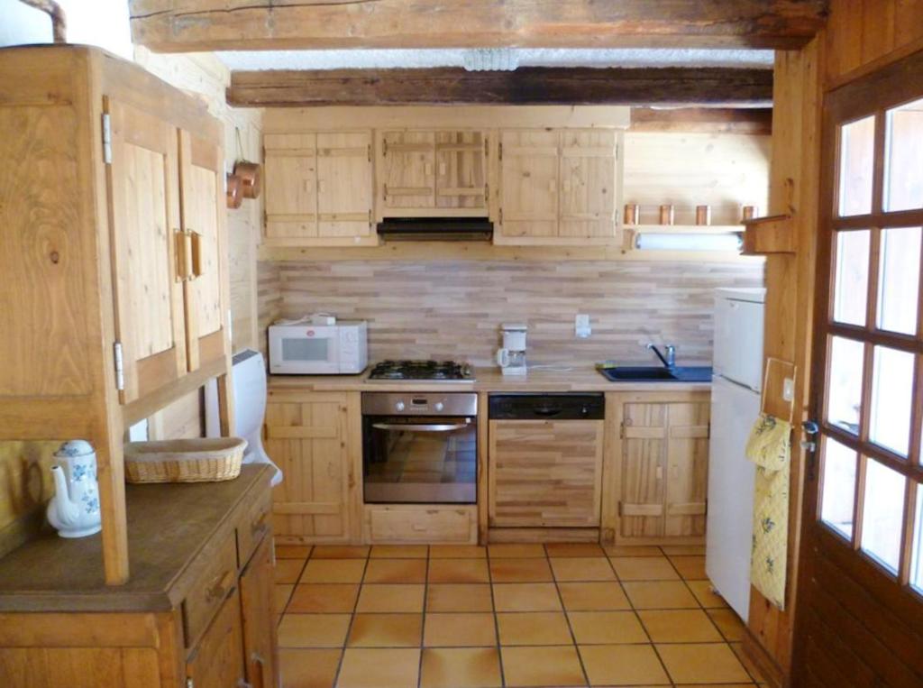 a kitchen with wooden cabinets and a stove top oven at Maison chaleureuse à Notre-Dame-de-Bellecombe avec cheminée. in Notre-Dame-de-Bellecombe