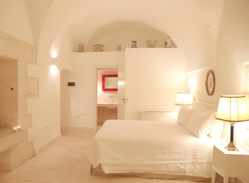 a white bedroom with a bed and a lamp at Casa d'Autore in Ostuni