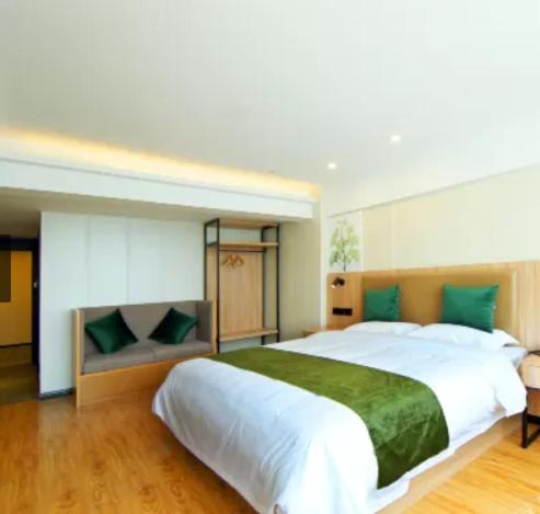 南京市にあるGreenTree Inn Nanjing Lukou Airportのベッドルーム(緑の枕が付く大きな白いベッド付)