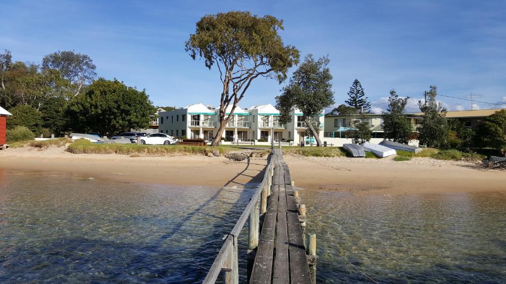 een houten brug over het water naast een strand bij Bayview Apartments in Merimbula