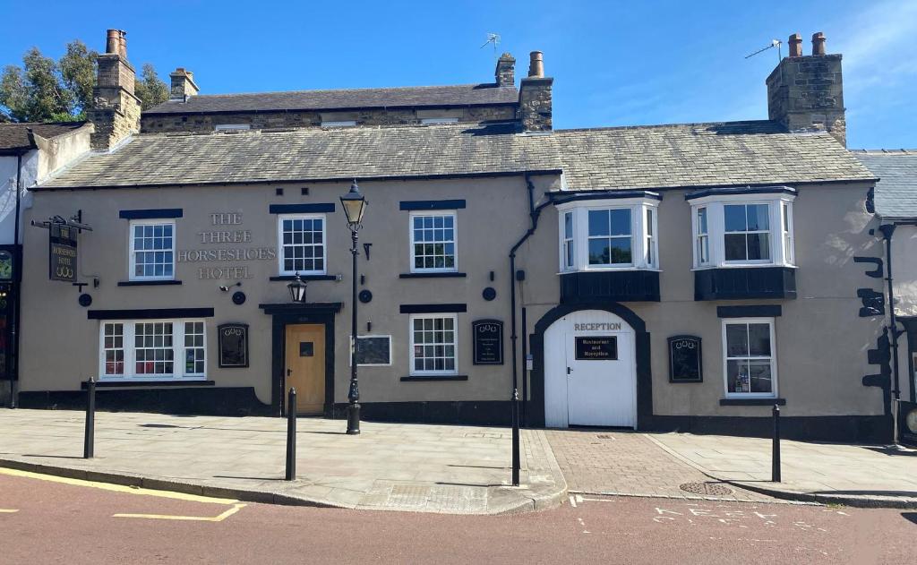 un vecchio edificio bianco con un cartello davanti di The Three Horseshoes Hotel a Barnard Castle