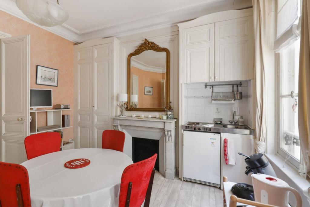 une cuisine avec une table blanche et des chaises rouges dans l'établissement Appartement des Embruns - Welkeys, à Trouville-sur-Mer