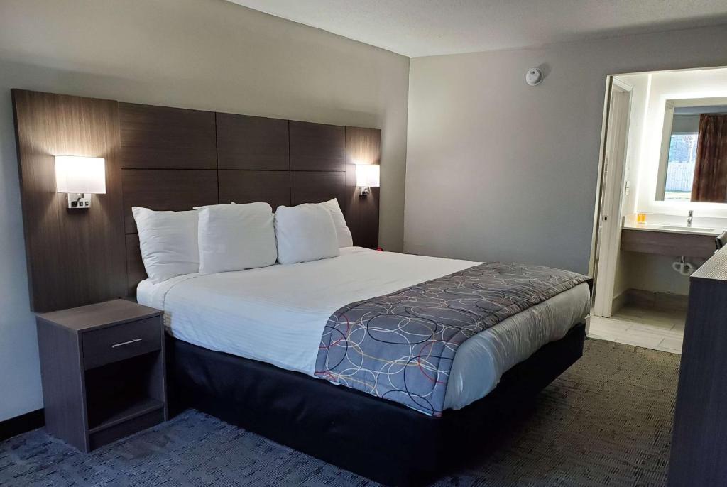 a hotel room with a large bed and a window at Days Inn & Suites by Wyndham Charleston Airport West in Charleston